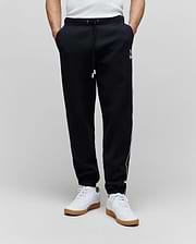 Mens Toby Track Pants in black French terry, featuring a relaxed fit, white drawstring, white Psycho Bunny skull logo on the left thigh, and white side stripes.