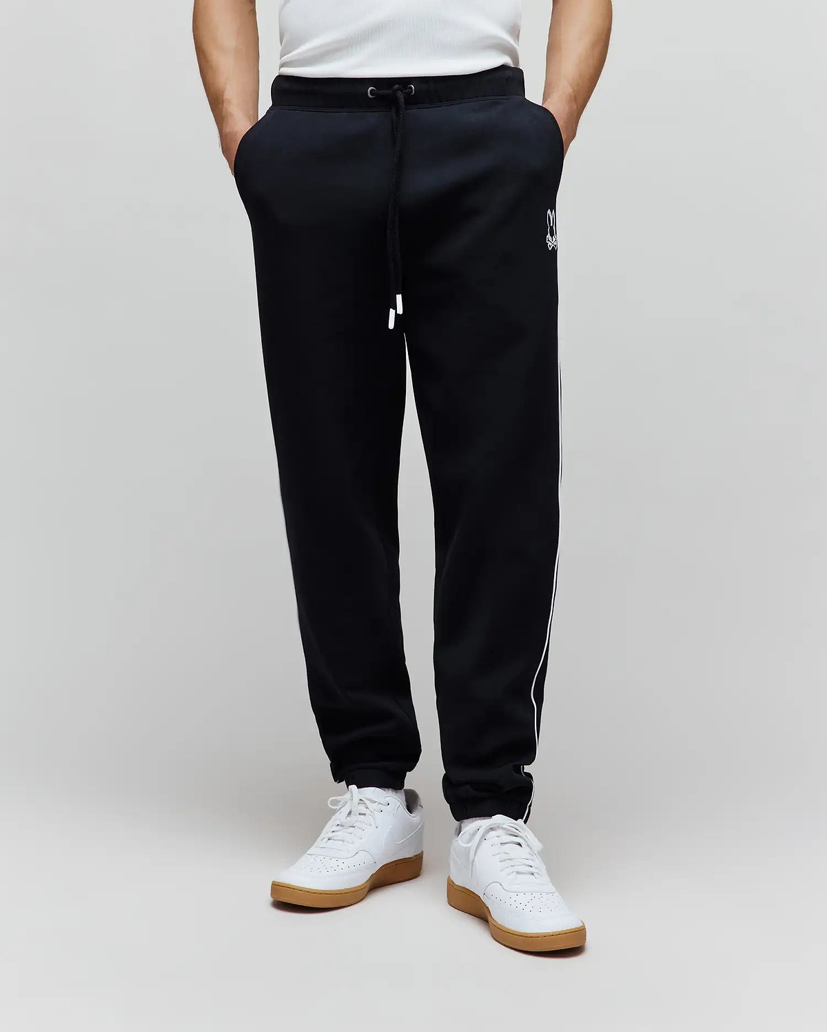 Mens Toby Track Pants in black French terry, featuring a relaxed fit, white drawstring, white Psycho Bunny skull logo on the left thigh, and white side stripes.
