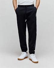 Mens Toby Track Pants in black French terry, featuring a relaxed fit, white drawstring, white Psycho Bunny skull logo on the left thigh, and white side stripes.
