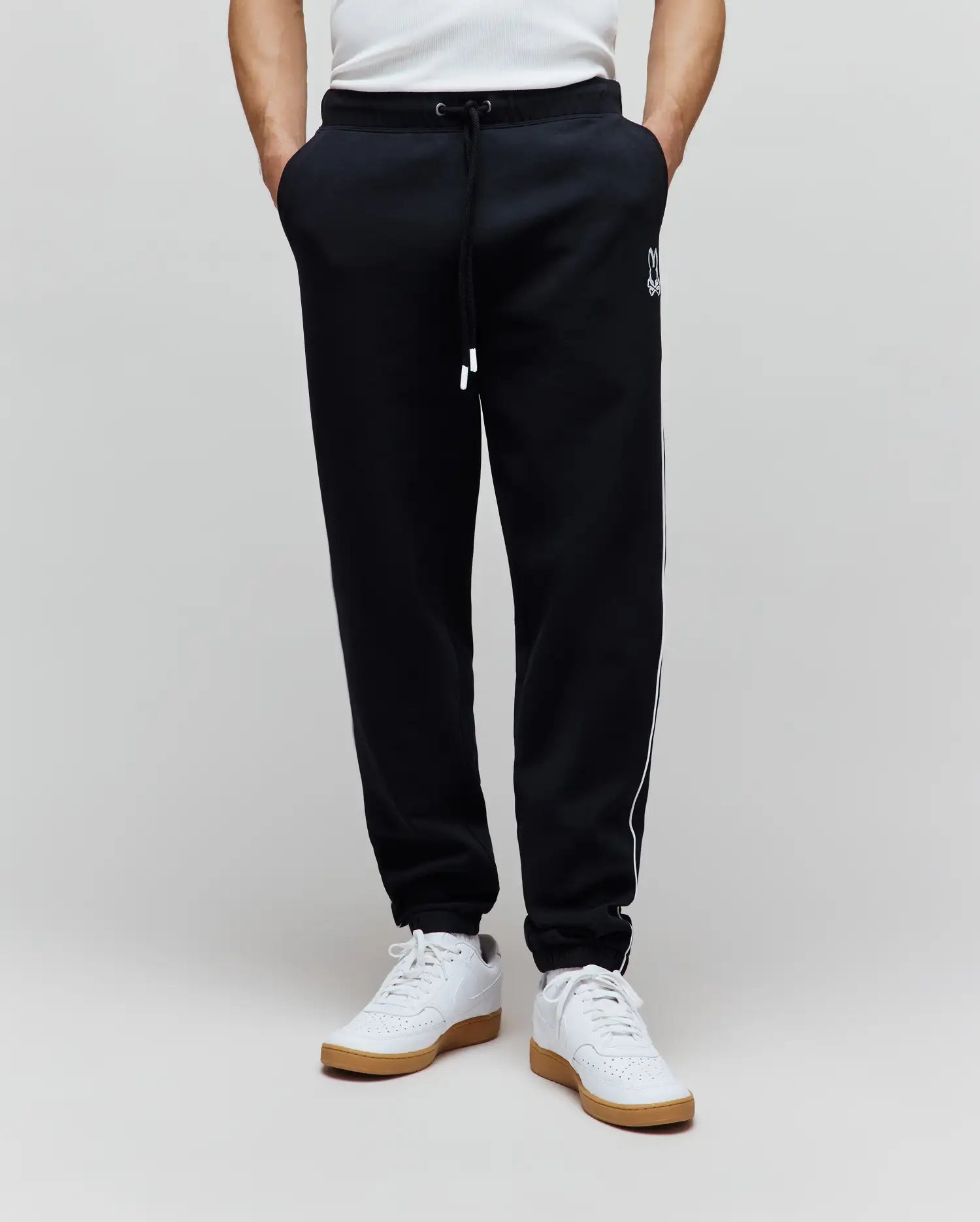 Mens Toby Track Pants in black French terry, featuring a relaxed fit, white drawstring, white Psycho Bunny skull logo on the left thigh, and white side stripes.