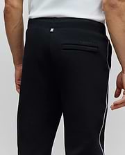 Mens Toby Track Pants, black, classic fit, smooth knit, with white Psycho Bunny skull logo on back waistband, tonal Psycho Bunny text on back pocket, and white side stripe.