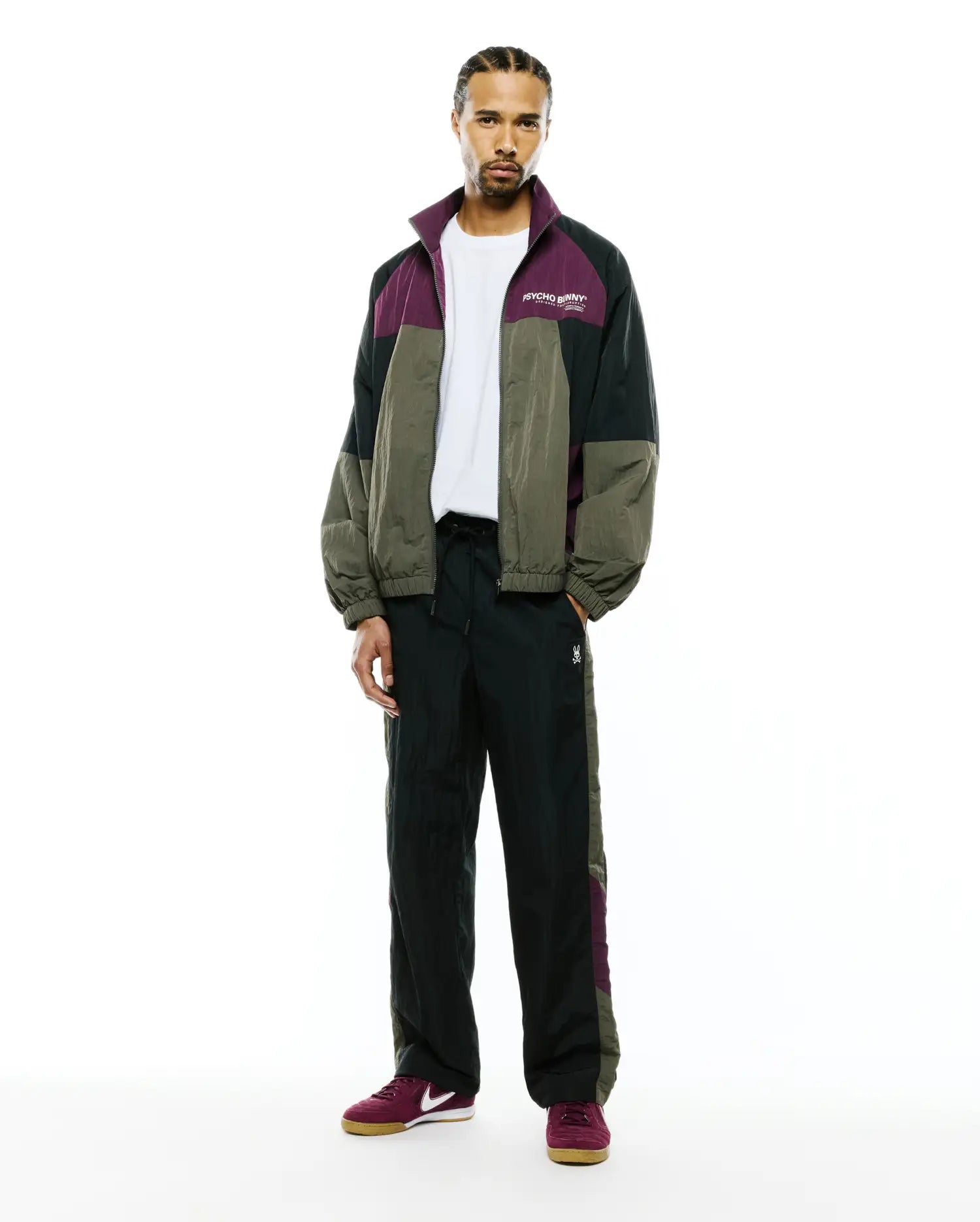 Relaxed crinkled nylon colorblock jacket in green, black, and purple with a white chest Psycho Bunny logo, matching Mens Alder Nylon Colorblock Pant with side panels and a small bunny skull.