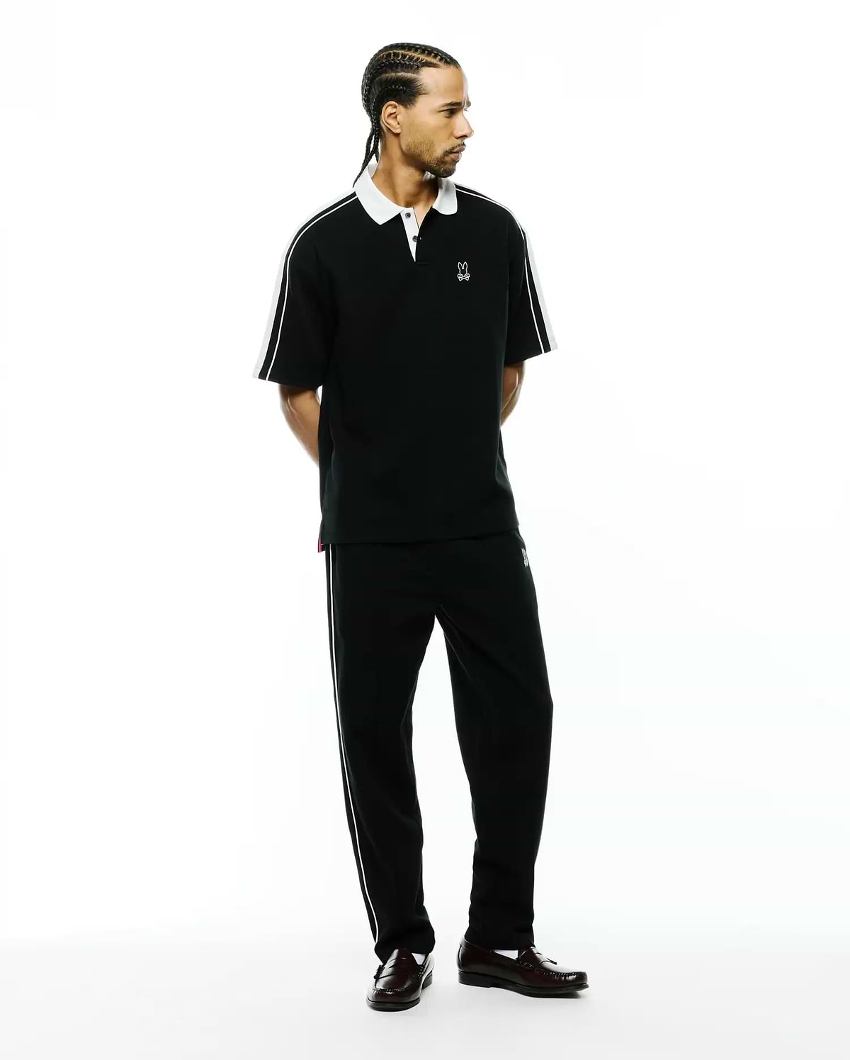 Black pique polo with white collar, sleeve stripes, and small embroidered Psycho Bunny logo, paired with Mens Ceano Track Pant, black with white side piping and a small bunny skull.