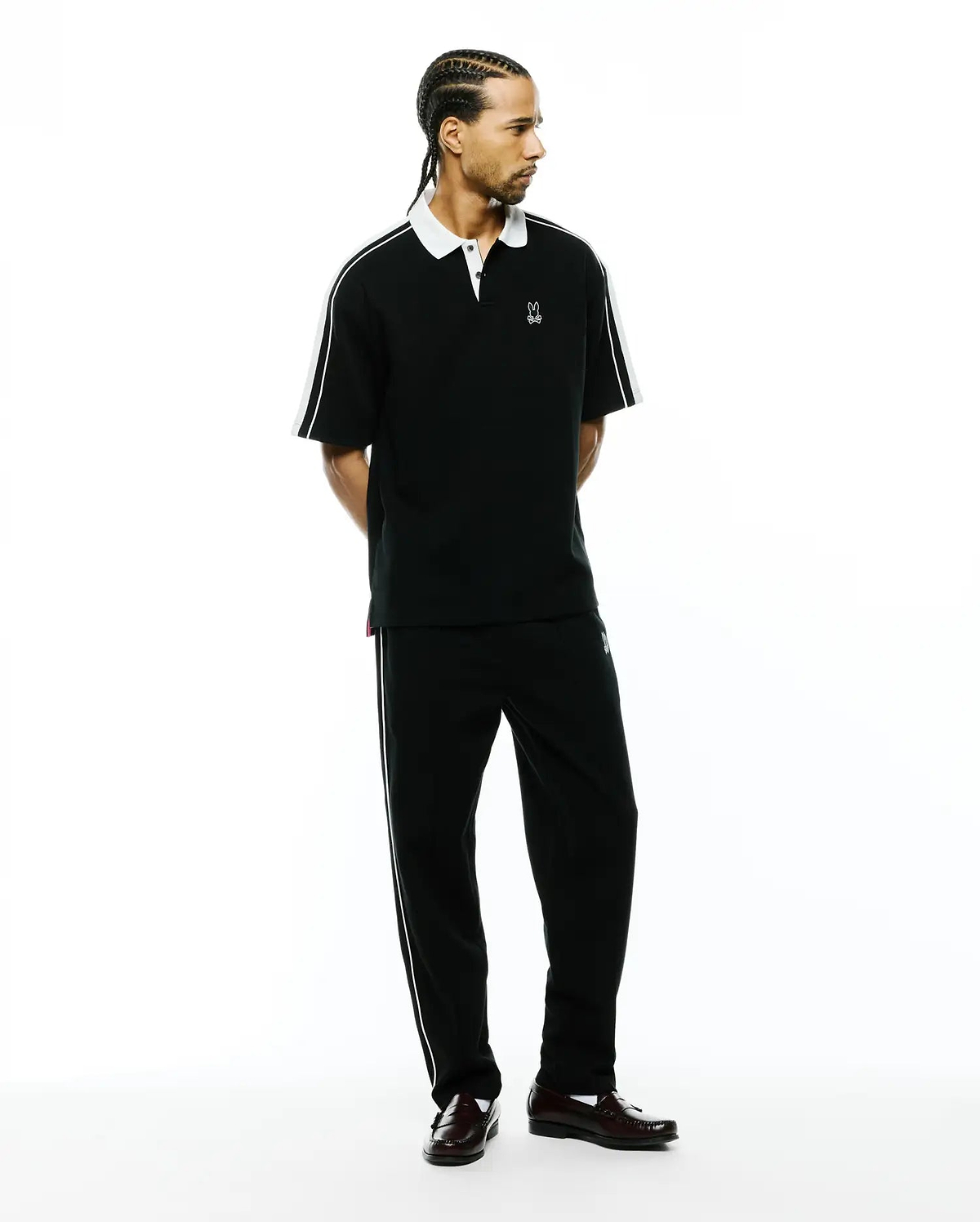 Black pique polo with white collar, sleeve stripes, and small embroidered Psycho Bunny logo, paired with Mens Ceano Track Pant, black with white side piping and a small bunny skull.