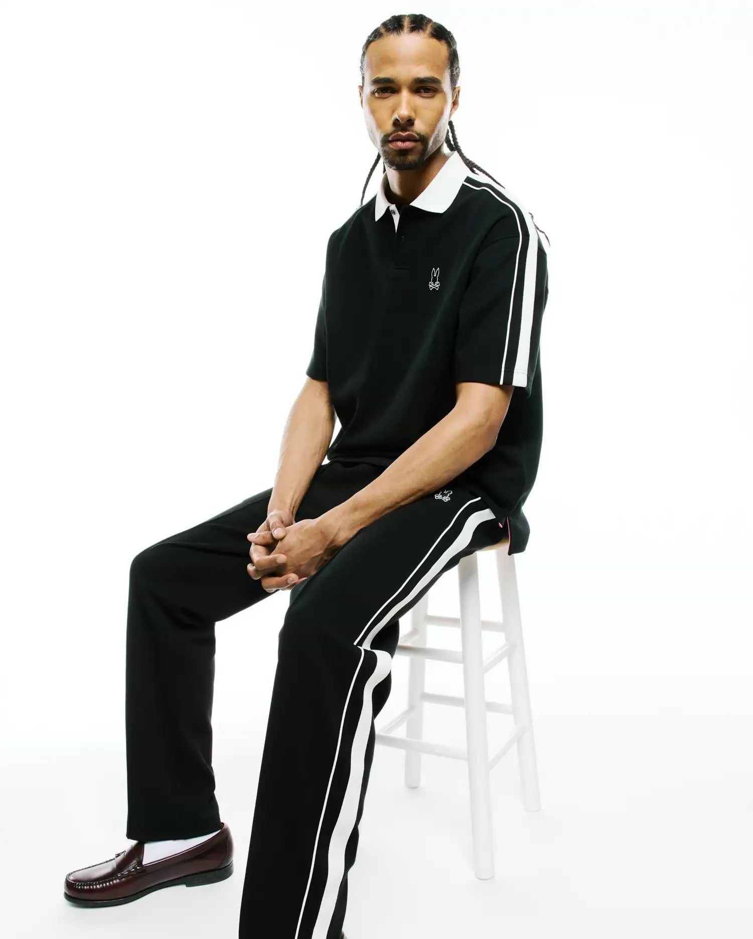 Black pique polo, classic fit, with white collar, sleeve stripes, and embroidered Psycho Bunny skull logo, plus Mens Ceano Track Pant with white side stripes and a thigh logo.