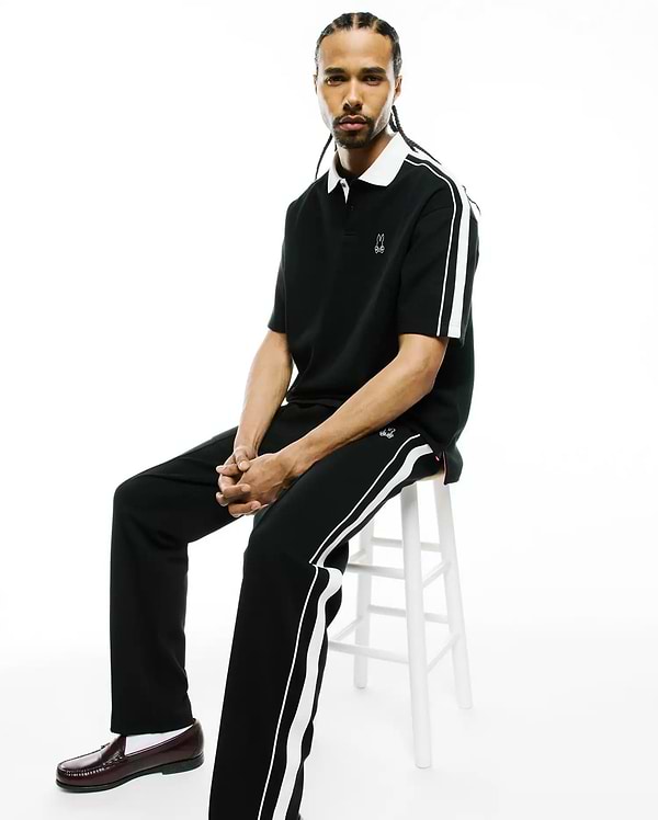 Black pique polo, classic fit, with white collar, sleeve stripes, and embroidered Psycho Bunny skull logo, plus Mens Ceano Track Pant with white side stripes and a thigh logo.