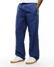 Mens Alder Nylon Pant in navy blue, featuring a relaxed fit, crinkled nylon texture, drawstring waist, and a small dark embroidered Psycho Bunny skull logo on the left thigh. (3)
