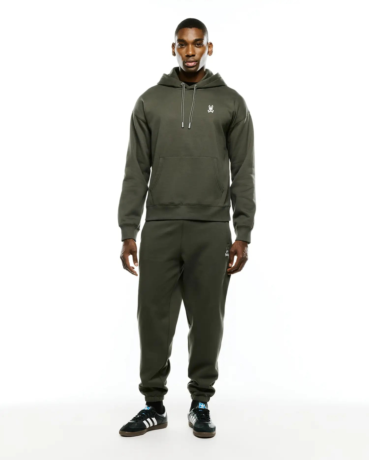 Olive green relaxed fit brushed fleece hoodie with white drawstring and embroidered Psycho Bunny skull chest logo. Paired with Mens Terrence Brushed Fleece Sweatpant, featuring an embroidered bunny skull thigh logo.