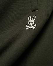 Mens Terrence Brushed Fleece Sweatpant in dark olive green, featuring a small, intricately embroidered white and silver Psycho Bunny skull logo on the upper leg, showcasing the soft brushed fleece knit texture.