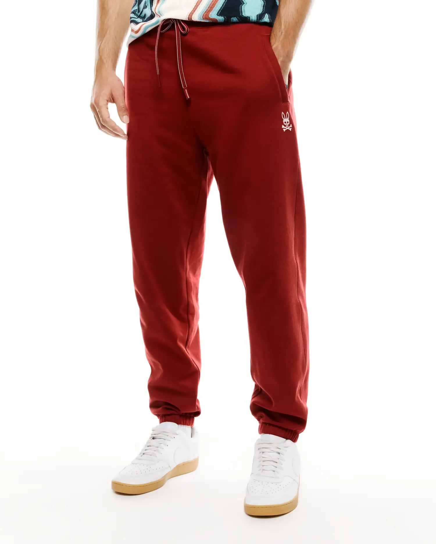 Mens Terrence Brushed Fleece Jogger in deep red, featuring a relaxed tapered fit, white drawstring, and small embroidered Psycho Bunny skull logo on the left thigh. (2)