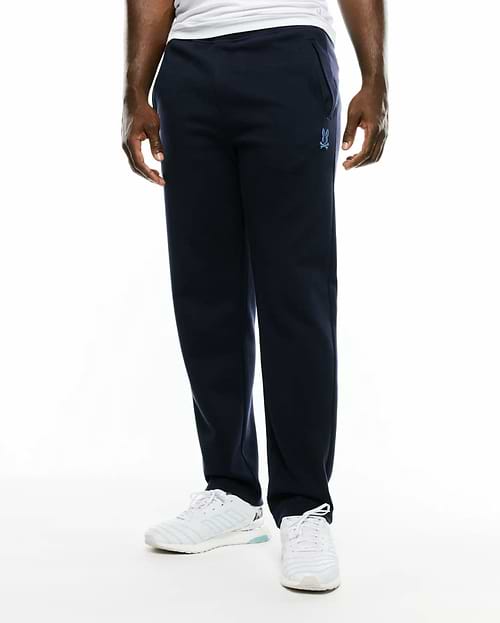 Men's Jacques Pique Track Pants in navy, featuring a relaxed fit and a small, light blue embroidered Psycho Bunny skull logo on the left thigh. (2)