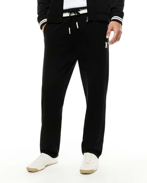 Men's Jacques Pique Track Pants in black, offering a relaxed fit with a white drawstring waist, subtle pique texture, and a small white embroidered Psycho Bunny skull logo on the right thigh. (2)