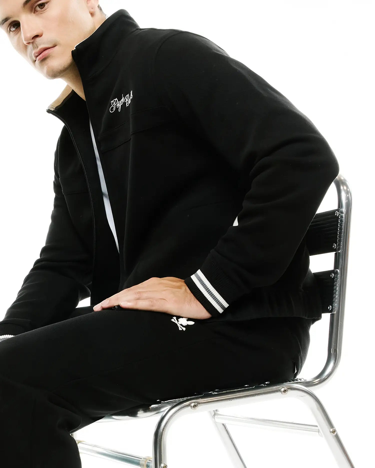 Black full-zip track jacket with cream collar lining, white embroidered script logo, striped cuffs, and matching Men's Jacques Pique Track Pants with white bunny skull logo. (4)