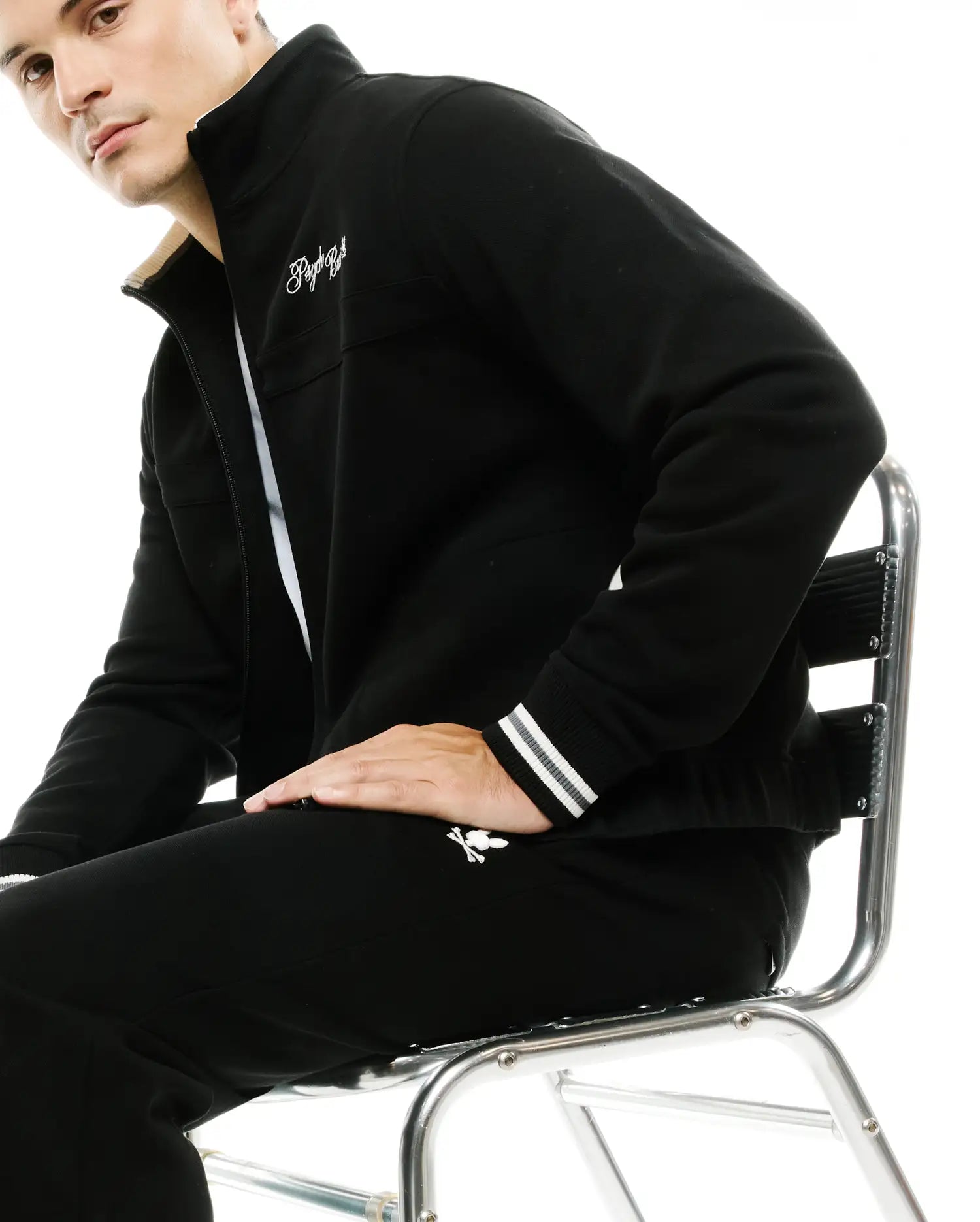Black full-zip track jacket with cream collar lining, white embroidered script logo, striped cuffs, and matching Men's Jacques Pique Track Pants with white bunny skull logo. (4)