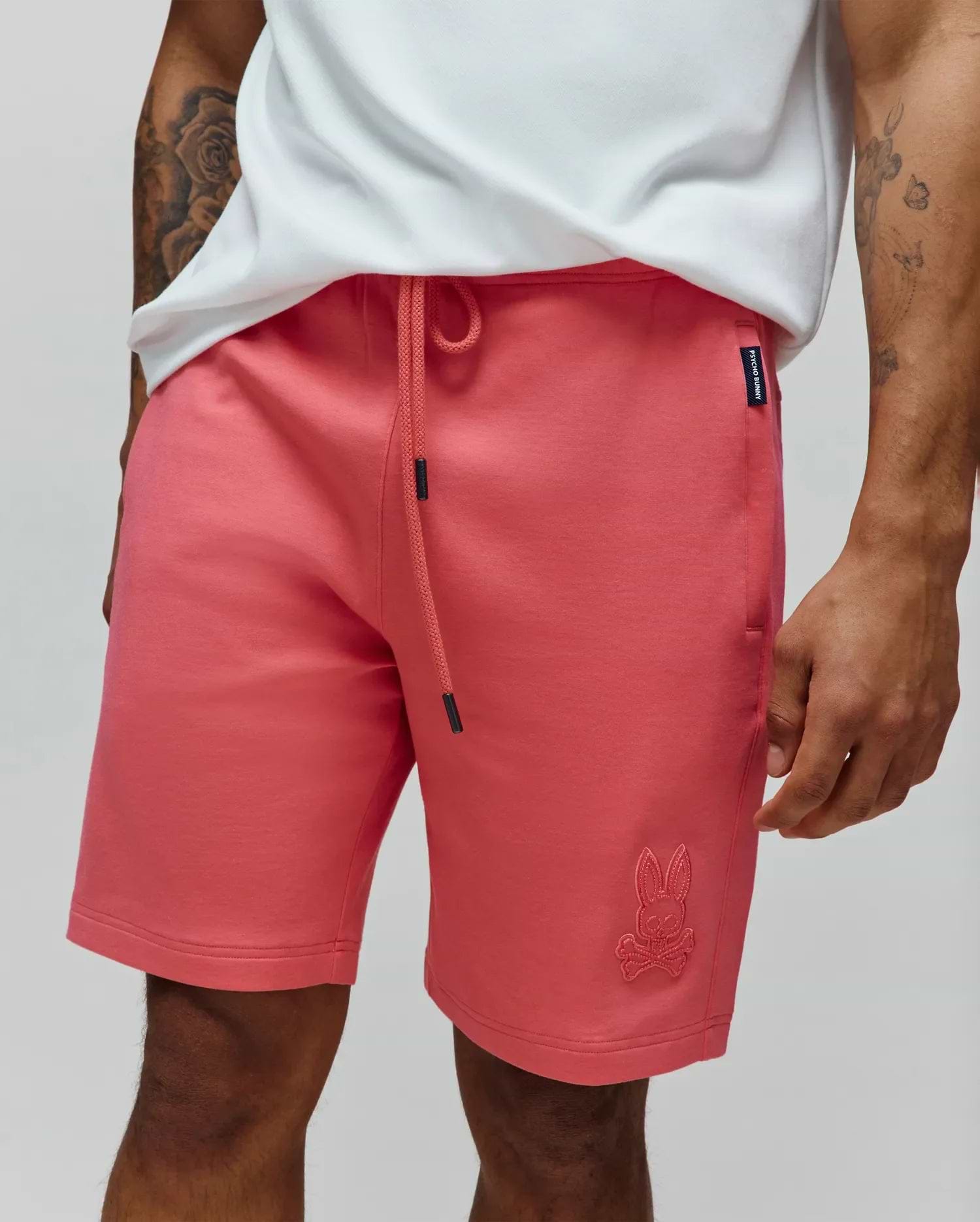 Mens Barry Short in coral pink, a relaxed fit jersey knit with a drawstring waist, featuring a tonal embroidered bunny skull logo on the lower left leg and a Psycho Bunny side tag. (2)