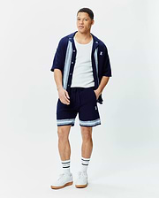 Navy Mens Giles Knit Short 7, relaxed fit, with light blue and white striped knit hem and embroidered Psycho Bunny skull, paired with a matching navy knit short-sleeve shirt with striped placket and chest logo.