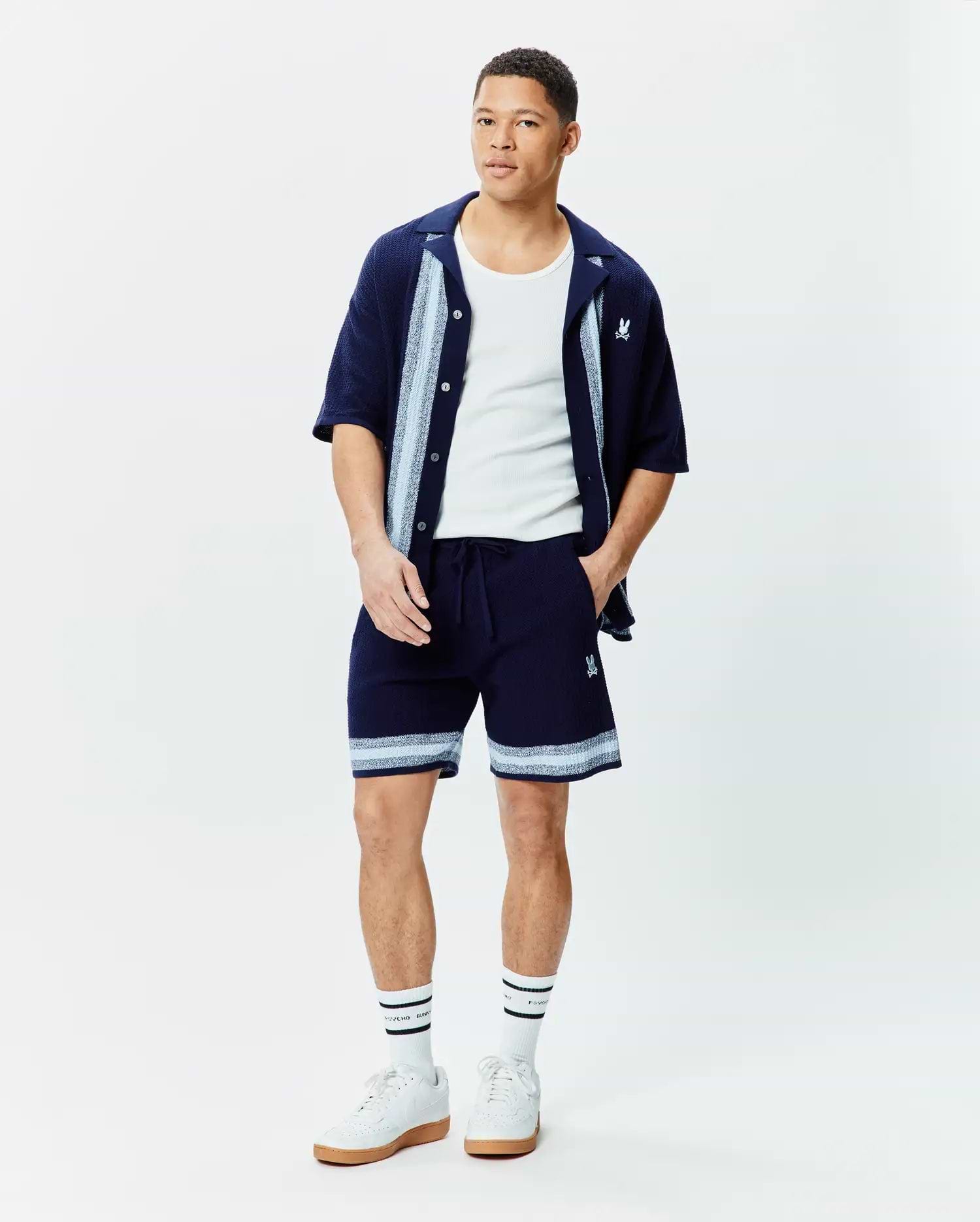 Navy Mens Giles Knit Short 7, relaxed fit, with light blue and white striped knit hem and embroidered Psycho Bunny skull, paired with a matching navy knit short-sleeve shirt with striped placket and chest logo.