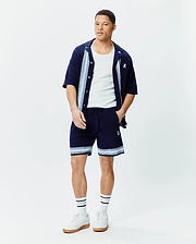 Navy Mens Giles Knit Short 7, relaxed fit, with light blue and white striped knit hem and embroidered Psycho Bunny skull, paired with a matching navy knit short-sleeve shirt with striped placket and chest logo.