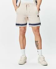 Mens Giles Knit Short 7, a cream textured knit short with navy and white striped hem, featuring a small embroidered Psycho Bunny skull logo on the left thigh and a drawstring waist.