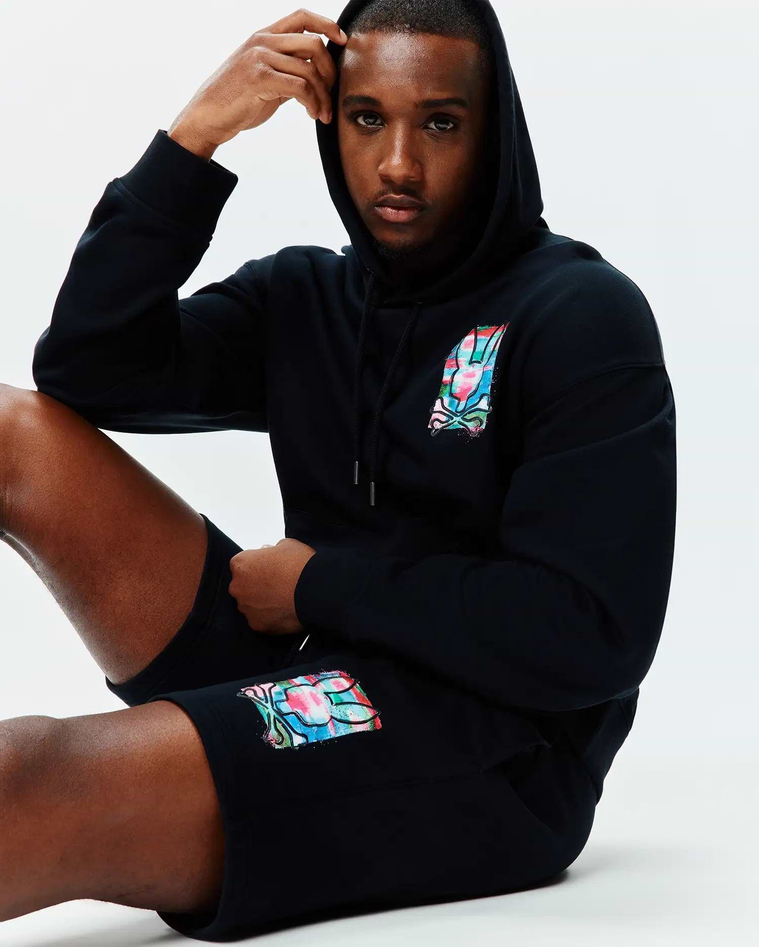 Black relaxed fit hoodie and Mens Isaac Print Short, both in soft jersey, featuring a vibrant multi-color Psycho Bunny skull logo on the left chest and left thigh.