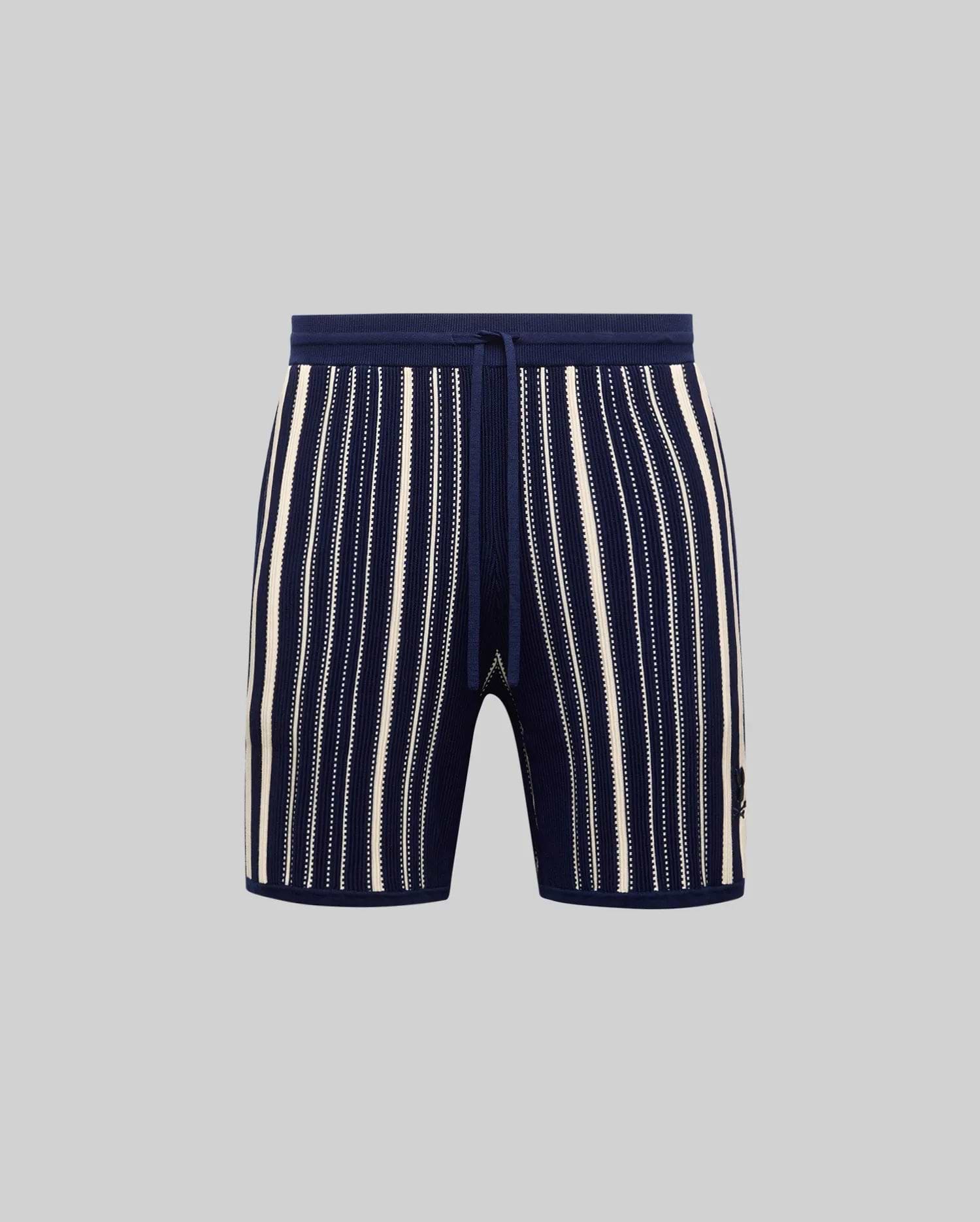 Mens Cliff Knit Short in navy ribbed knit with cream vertical stripes, some solid, some dotted, featuring a drawstring waist and small embroidered Psycho Bunny skull logo on the lower right leg.