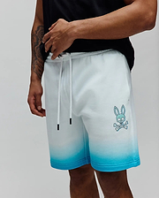 Mens Dax Sweatshort in a white to vibrant blue ombre fade, featuring a relaxed fit, soft French terry fabric, and a prominent light blue Psycho Bunny skull and crossbones logo on the left thigh. (2)