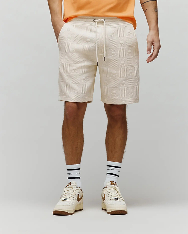 Mens Dustin Sweatshort, cream relaxed fit with all-over embossed Psycho Bunny skull and checkered pattern, textured knit fabric, drawstring waist.