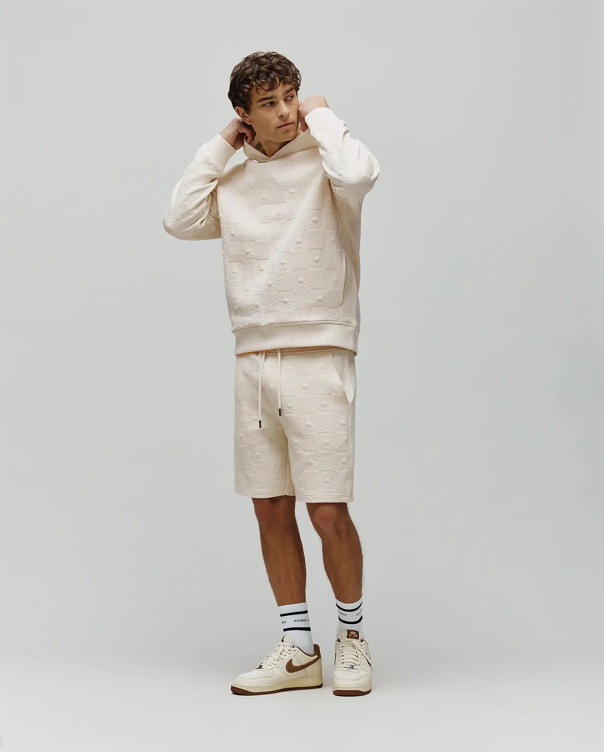 Cream relaxed fit hoodie and matching Mens Dustin Sweatshort, both featuring an all-over embossed Psycho Bunny skull pattern on a soft, textured knit fabric. (4)