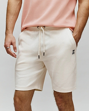 Mens Maxton Waffle Sweatshort in cream, featuring a relaxed fit, waffle knit texture, drawstring waist with black tips, and a small embroidered black Psycho Bunny skull logo on the left thigh.