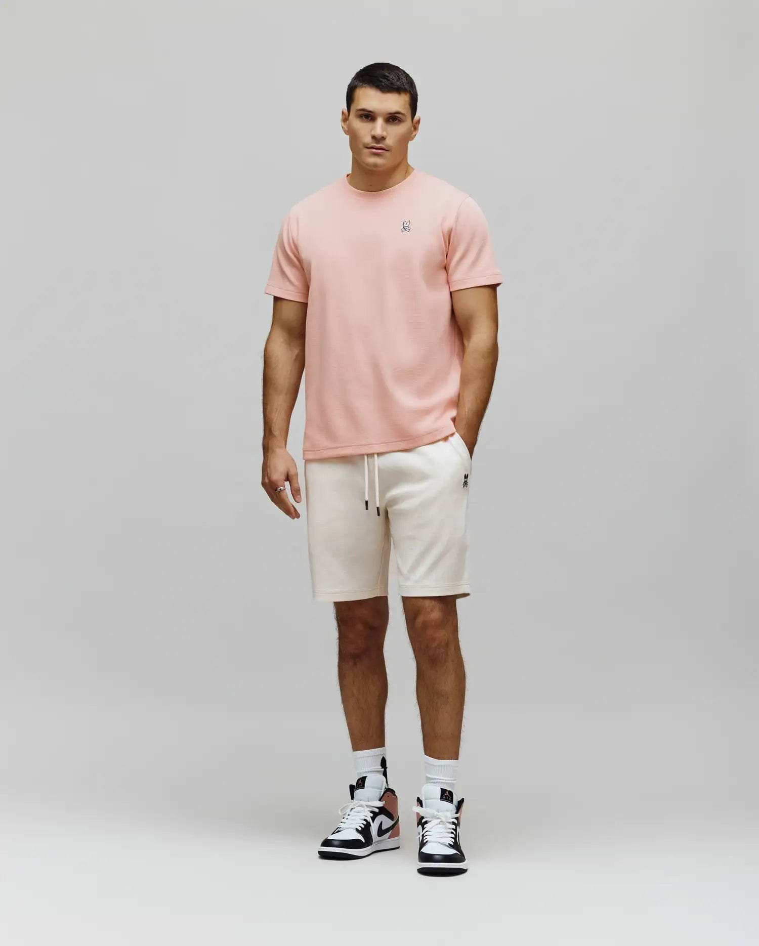 Peach textured t-shirt with a small embroidered Psycho Bunny skull logo on the left chest, paired with cream Mens Maxton Waffle Sweatshort featuring a drawstring waist and a small embroidered Psycho Bunny logo on the left thigh.
