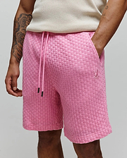 Mens Garen Knit Short, a relaxed fit pink knit short featuring a prominent woven checkerboard texture, a drawstring waist with black tips, and a small embroidered Psycho Bunny skull logo on the right thigh. (2)