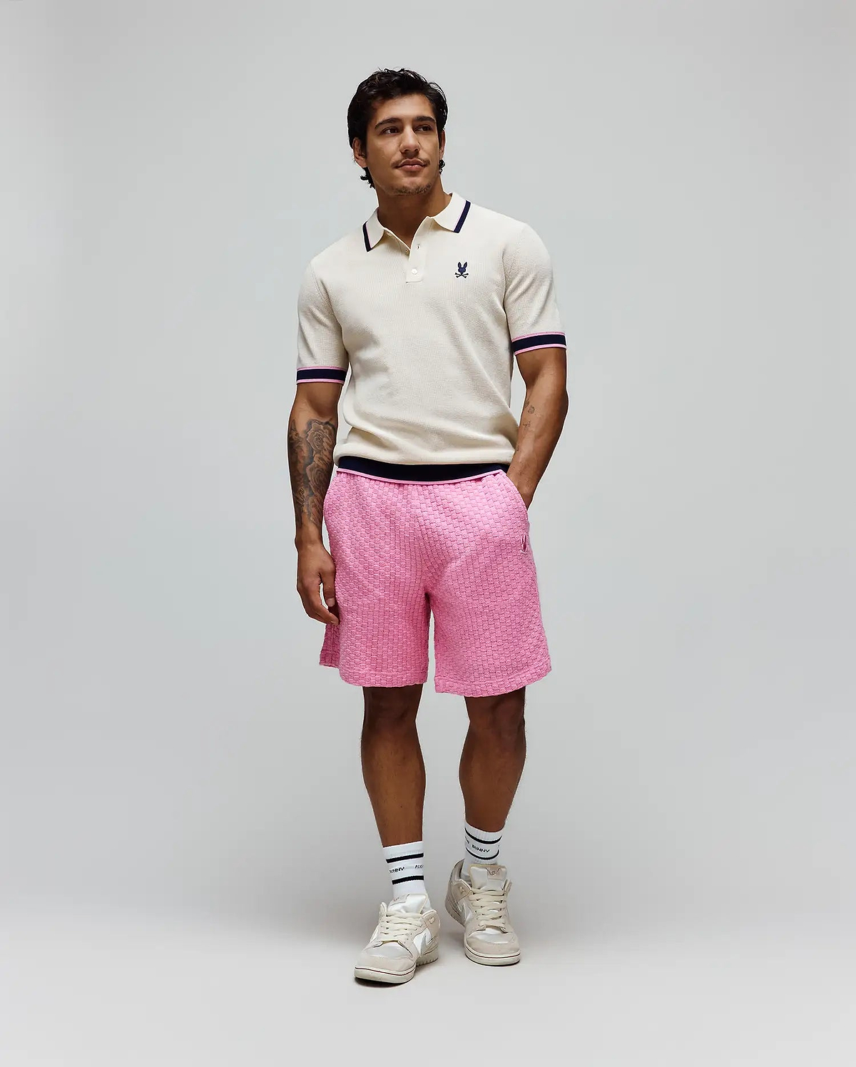 Cream knit polo with navy and pink striped collar/cuffs and embroidered Psycho Bunny logo, paired with bright pink textured knit Mens Garen Knit Short featuring a navy waistband and small embroidered logo. (3)