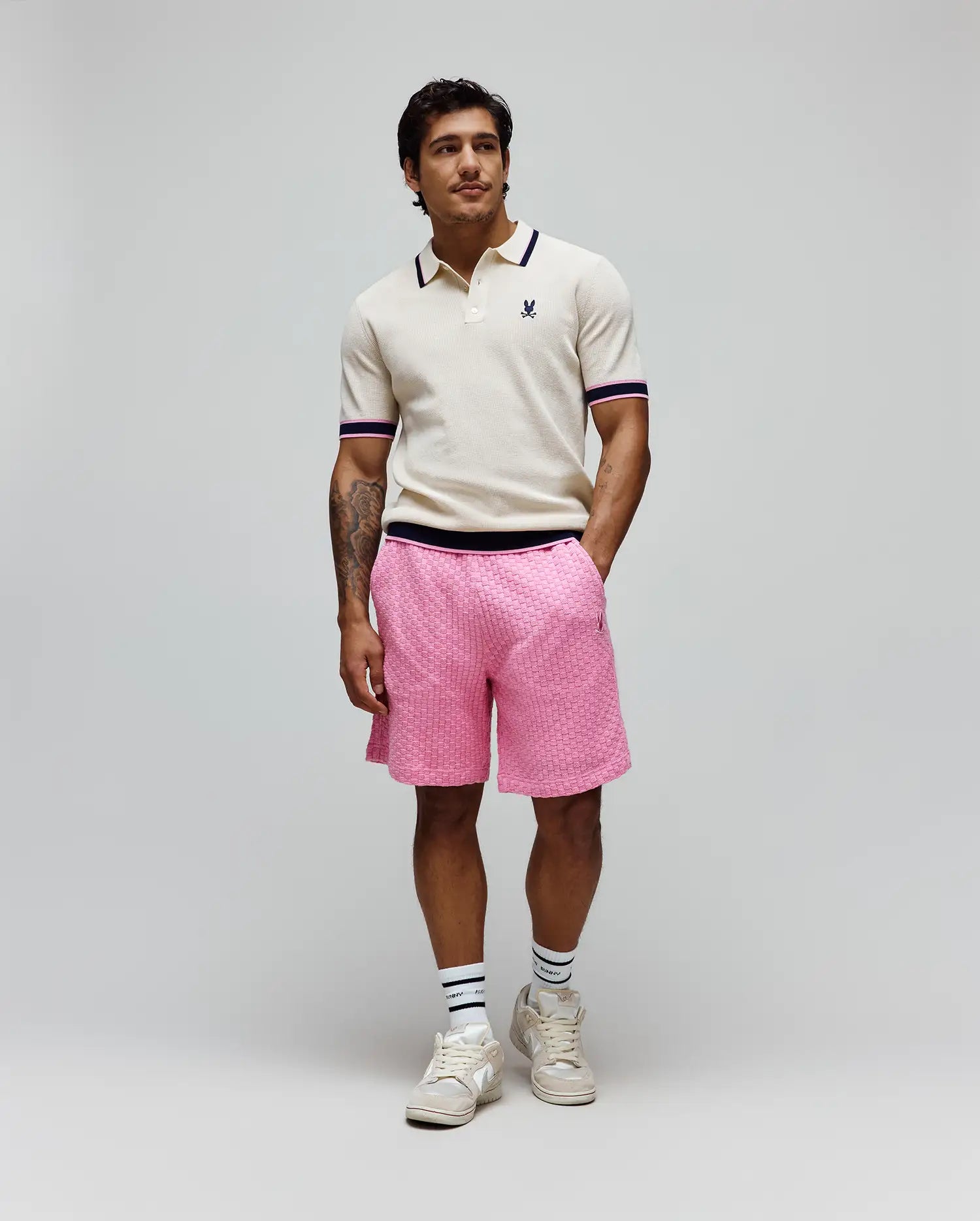 Cream knit polo with navy and pink striped collar/cuffs and embroidered Psycho Bunny logo, paired with bright pink textured knit Mens Garen Knit Short featuring a navy waistband and small embroidered logo. (3)