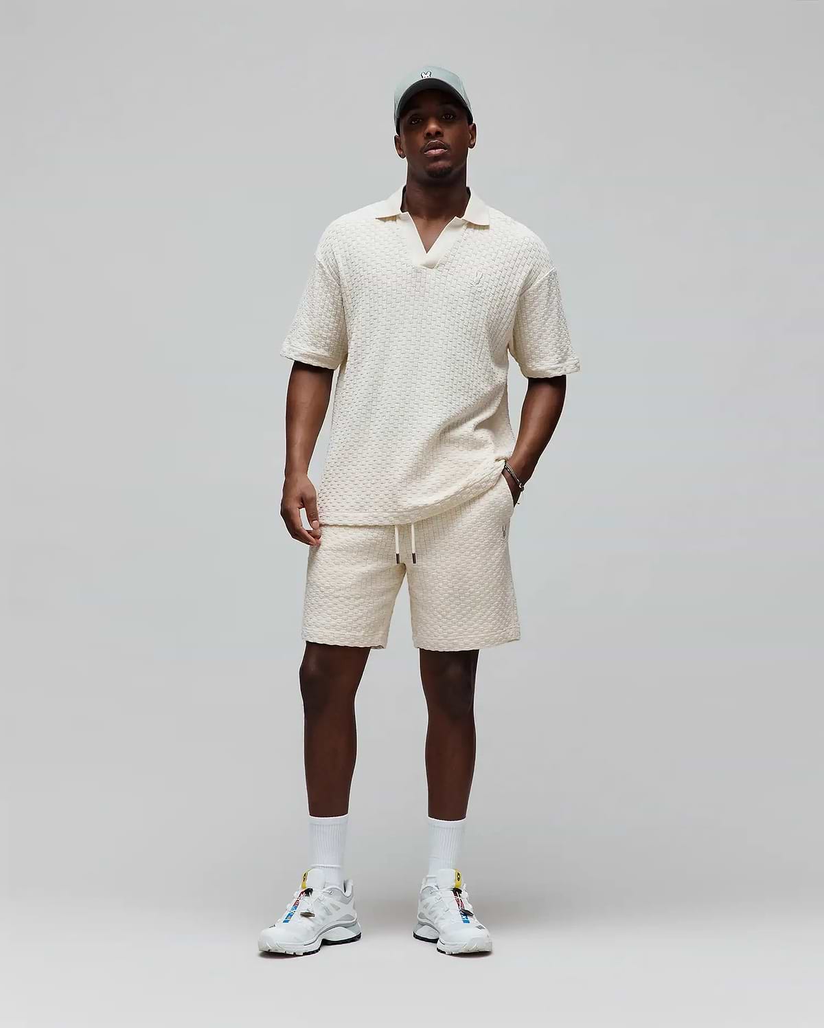 Cream textured knit polo and Mens Garen Knit Short set, both relaxed fit with small embroidered Psycho Bunny skull logos, polo on chest, shorts on left leg, shorts also have drawstring waist. (3)