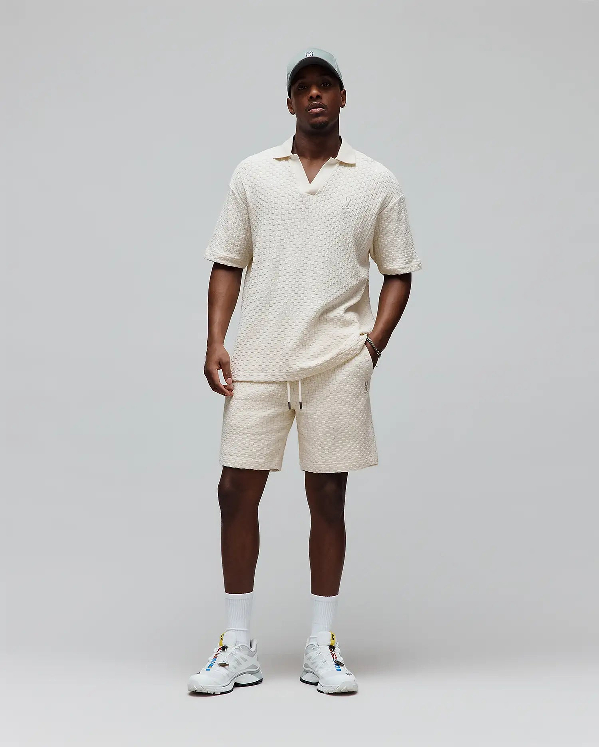 Cream textured knit polo and Mens Garen Knit Short set, both relaxed fit with small embroidered Psycho Bunny skull logos, polo on chest, shorts on left leg, shorts also have drawstring waist. (3)