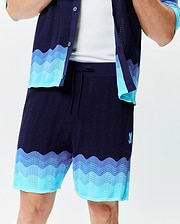 Mens Holden Knit Short in navy with a wavy knit texture, featuring light blue and purple-blue wave patterns at the hem, and a small embroidered Psycho Bunny logo on the left thigh.