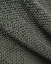 Mens Devon Knit Short 7, in deep olive green, crafted from a luxurious, soft, and breathable textured knit fabric with a distinctive raised, dimpled pattern.