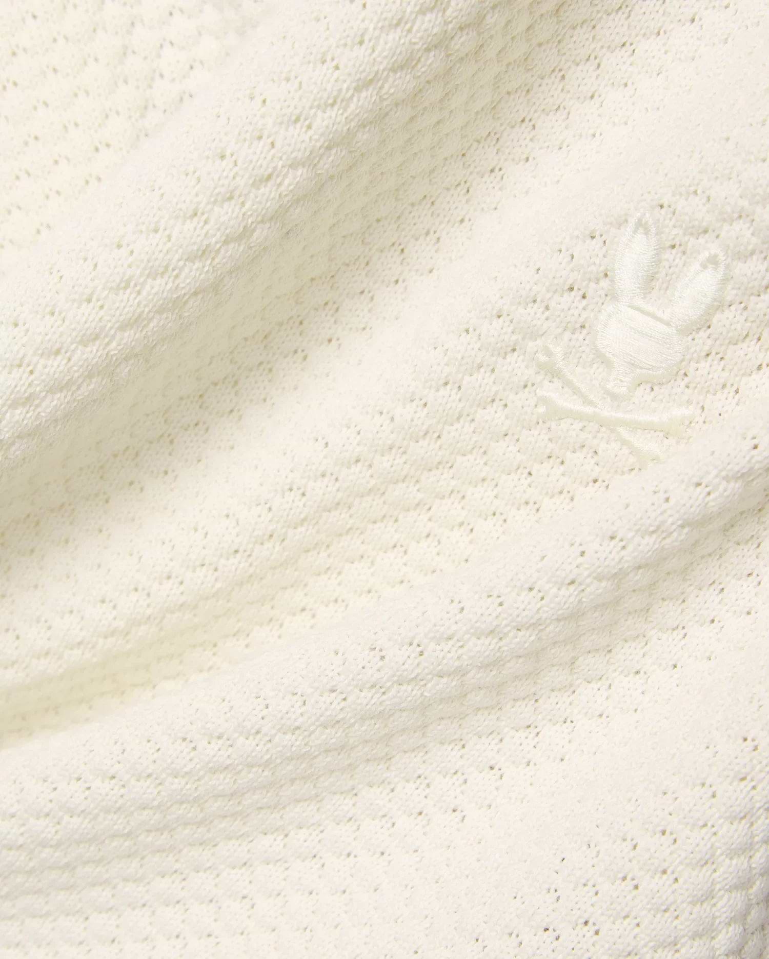 Mens Devon Knit Short in premium cream, featuring a soft, subtly patterned open knit fabric and a small, tone-on-tone embroidered Psycho Bunny skull logo detail.