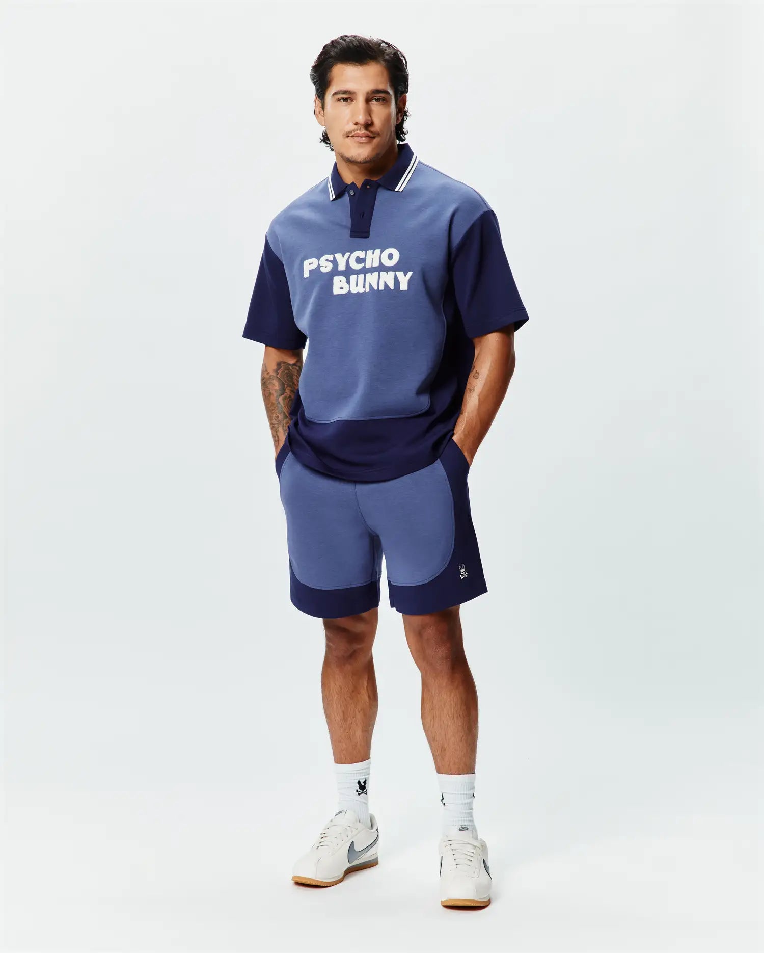 Relaxed fit two-tone blue jersey polo with large white PSYCHO BUNNY chest graphic, striped collar, and matching color-blocked Mens Kelly Short featuring a small embroidered skull logo. (4)