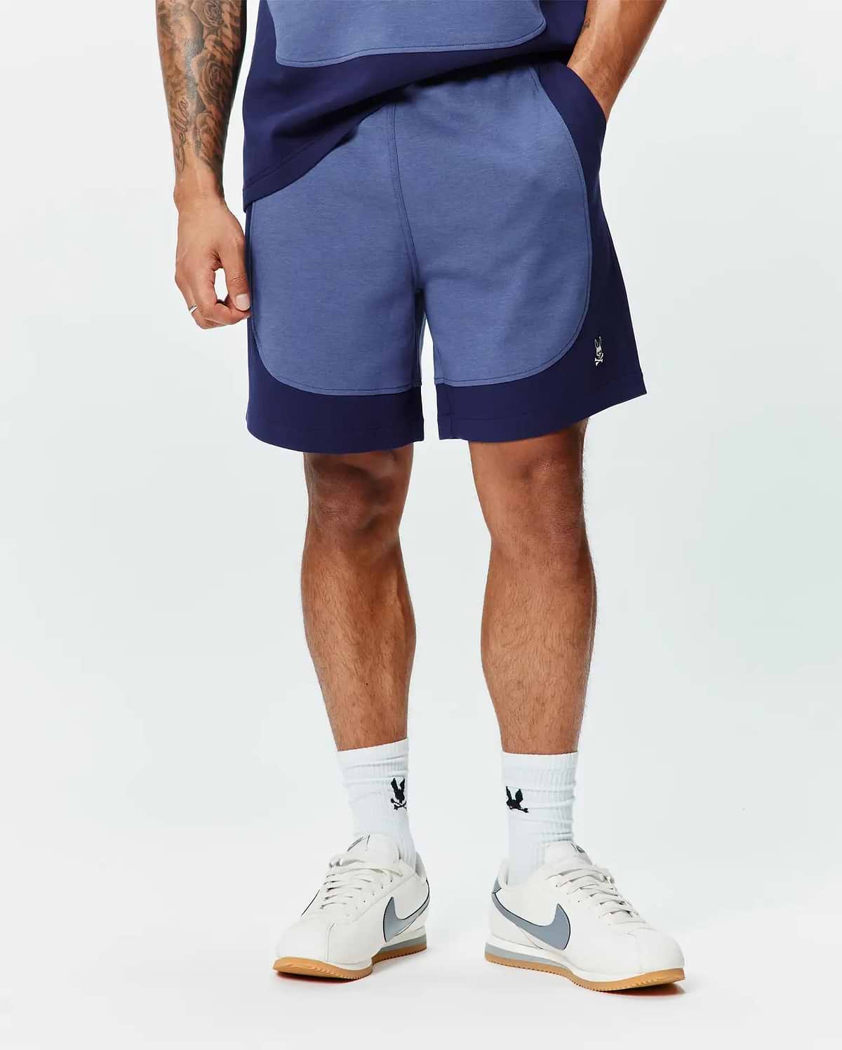 Premium Mens Kelly Short, a relaxed fit heathered blue short with dark navy color-block panels and a small embroidered white Psycho Bunny skull logo on the left leg. (1)