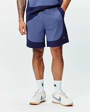 Premium Mens Kelly Short, a relaxed fit heathered blue short with dark navy color-block panels and a small embroidered white Psycho Bunny skull logo on the left leg. (1)