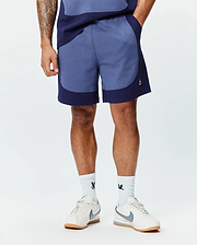 Premium Mens Kelly Short, a relaxed fit heathered blue short with dark navy color-block panels and a small embroidered white Psycho Bunny skull logo on the left leg. (1)