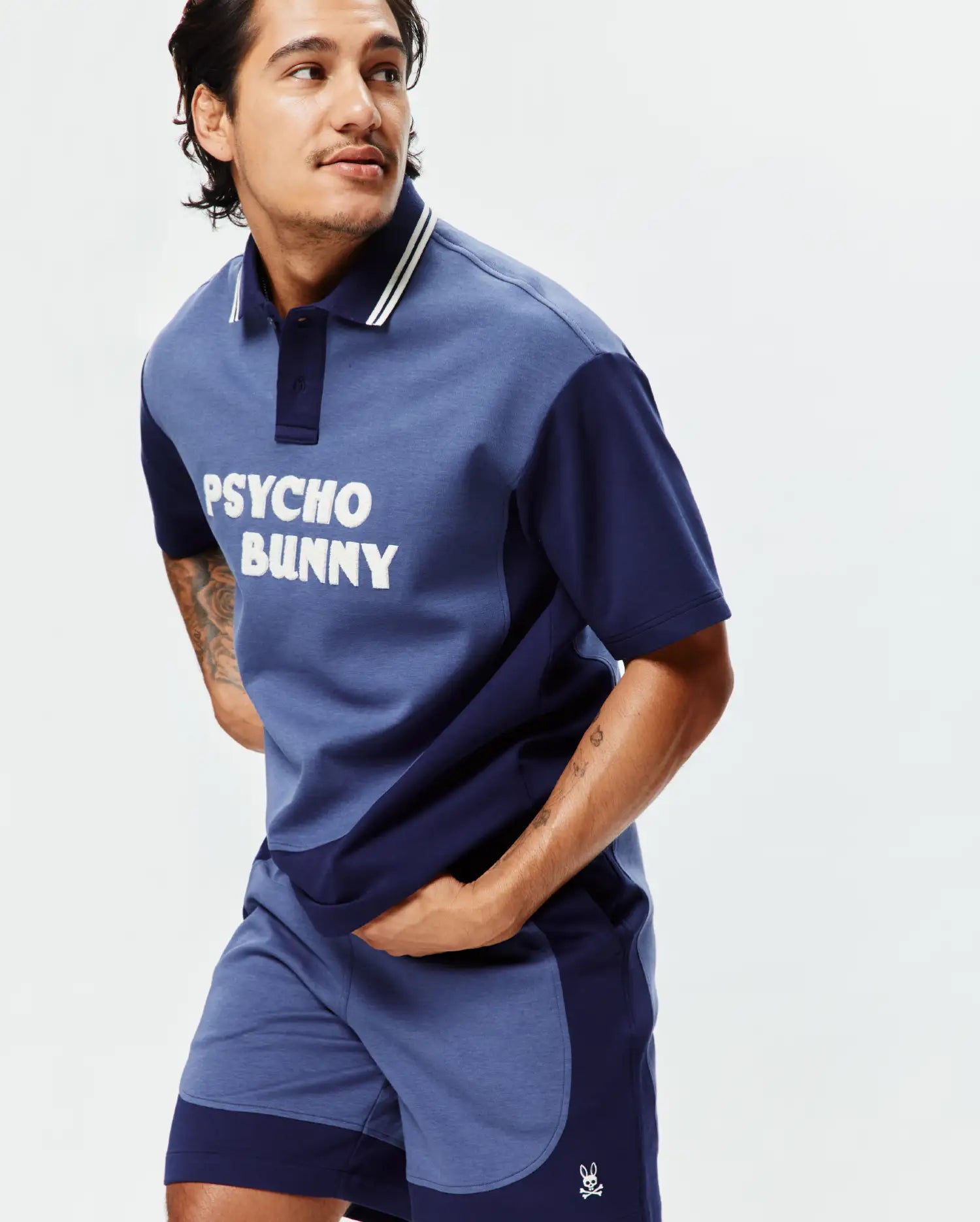Two-tone blue jersey polo with white PSYCHO BUNNY chest graphic and striped collar, paired with matching color-block Mens Kelly Short featuring an embroidered bunny skull logo. (2)