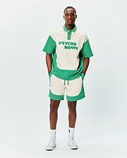 Relaxed fit cream and green color block jersey polo with large PSYCHO BUNNY text, paired with MENS KELLY SHORT featuring wavy green panels and embroidered bunny skull logo. (3)