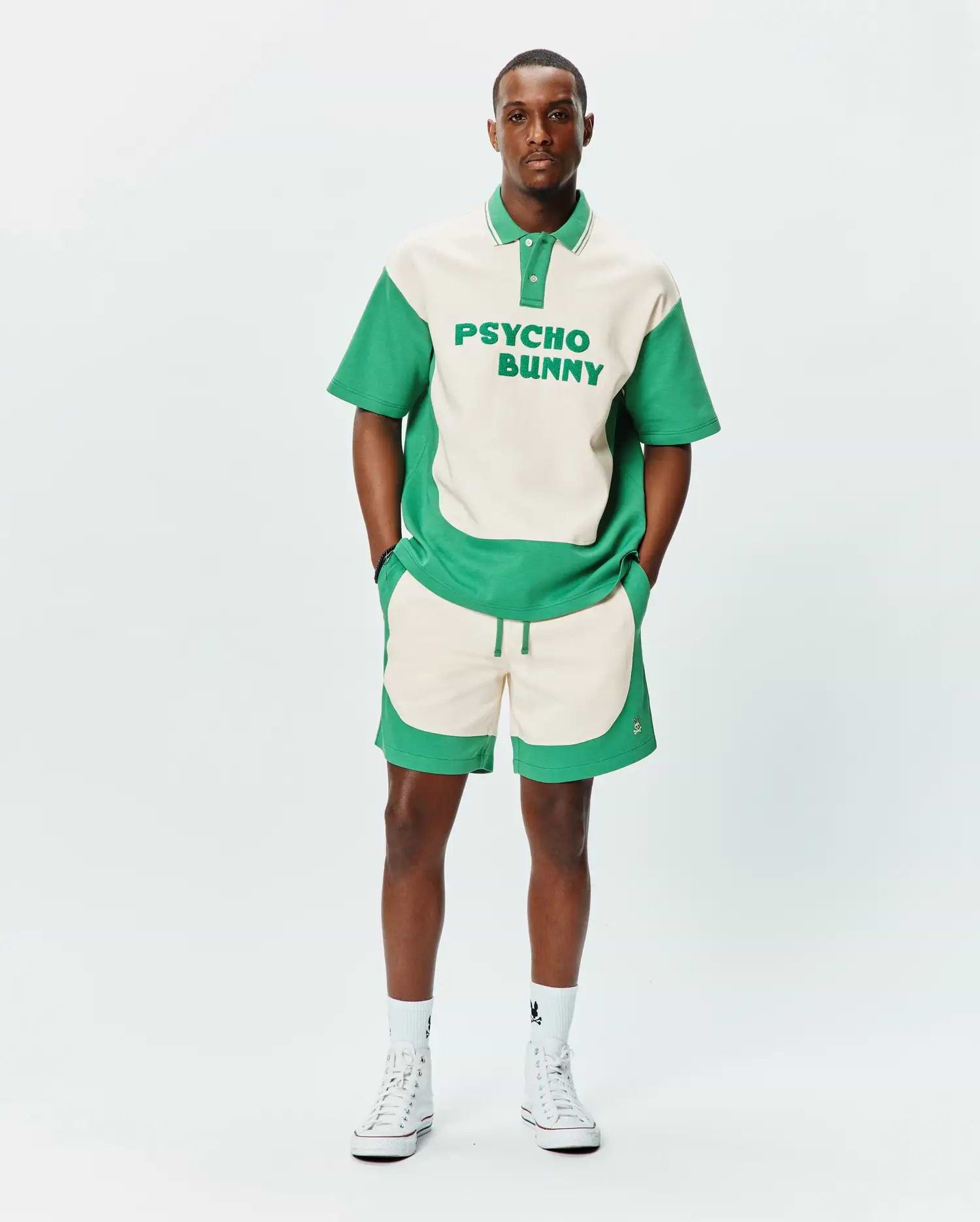 Relaxed fit cream and green color block jersey polo with large PSYCHO BUNNY text, paired with MENS KELLY SHORT featuring wavy green panels and embroidered bunny skull logo. (3)