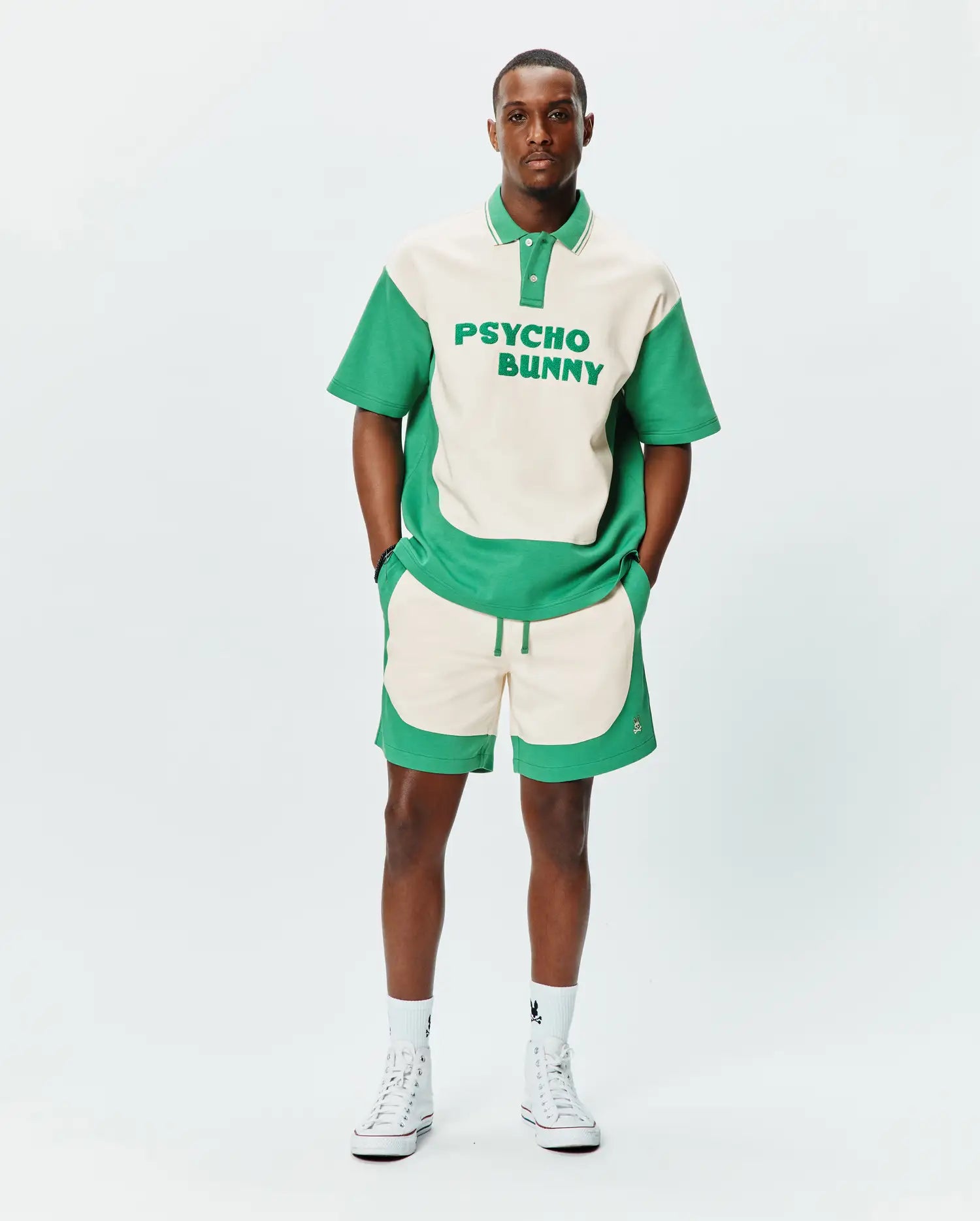 Relaxed fit cream and green color block jersey polo with large PSYCHO BUNNY text, paired with MENS KELLY SHORT featuring wavy green panels and embroidered bunny skull logo. (3)