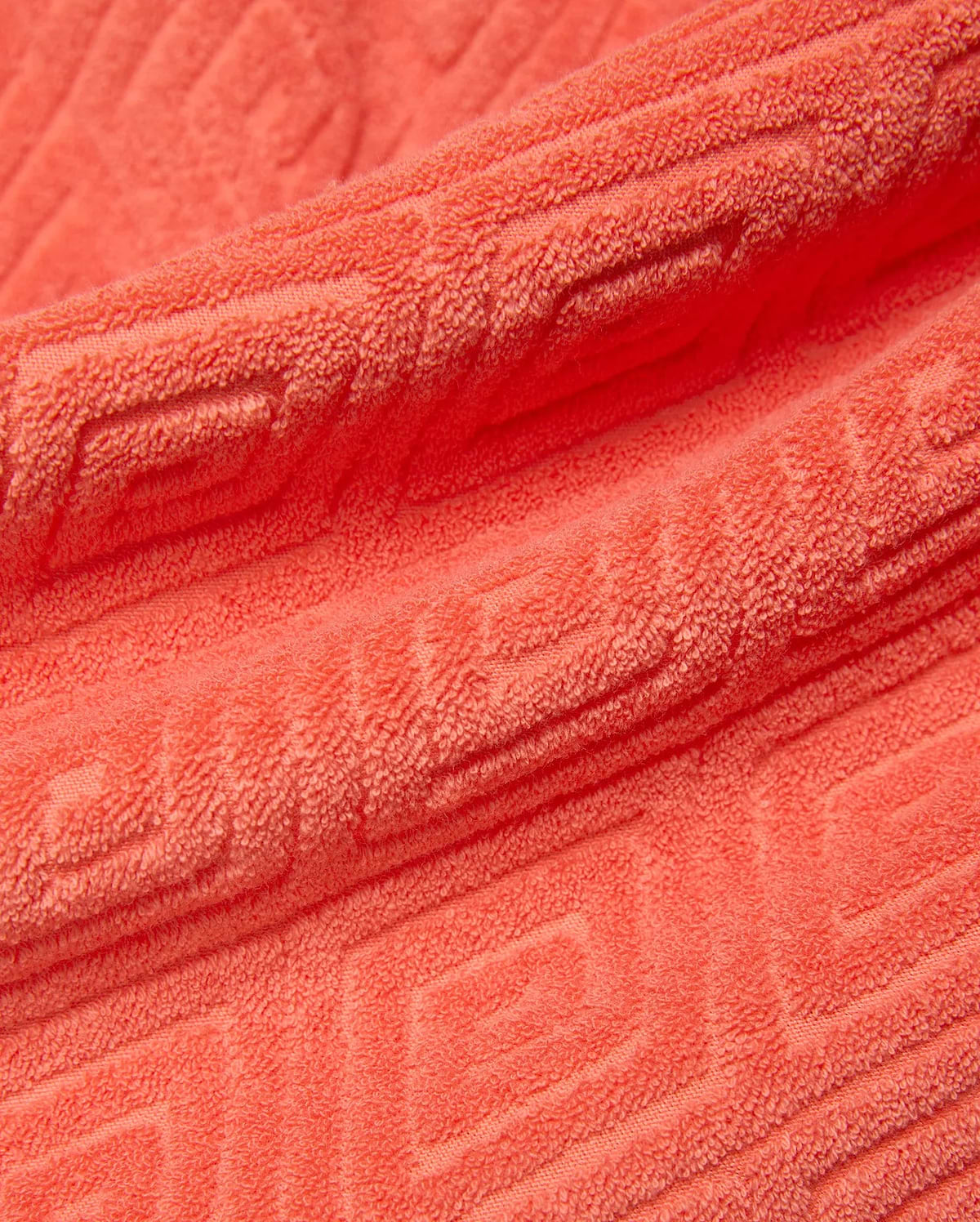 Mens Tristan Short in bold coral terry cloth, featuring a luxurious plush texture and an intricate, all-over embossed geometric maze pattern, reflecting refined streetwear style.
