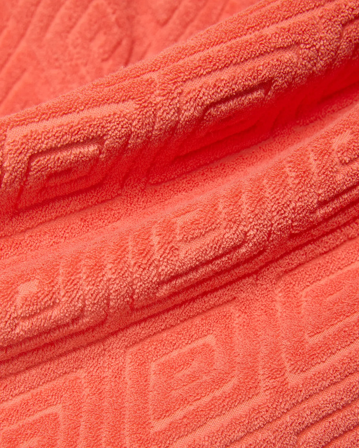 Mens Tristan Short in bold coral terry cloth, featuring a luxurious plush texture and an intricate, all-over embossed geometric maze pattern, reflecting refined streetwear style.