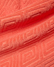 Mens Tristan Short in bold coral terry cloth, featuring a luxurious plush texture and an intricate, all-over embossed geometric maze pattern, reflecting refined streetwear style.