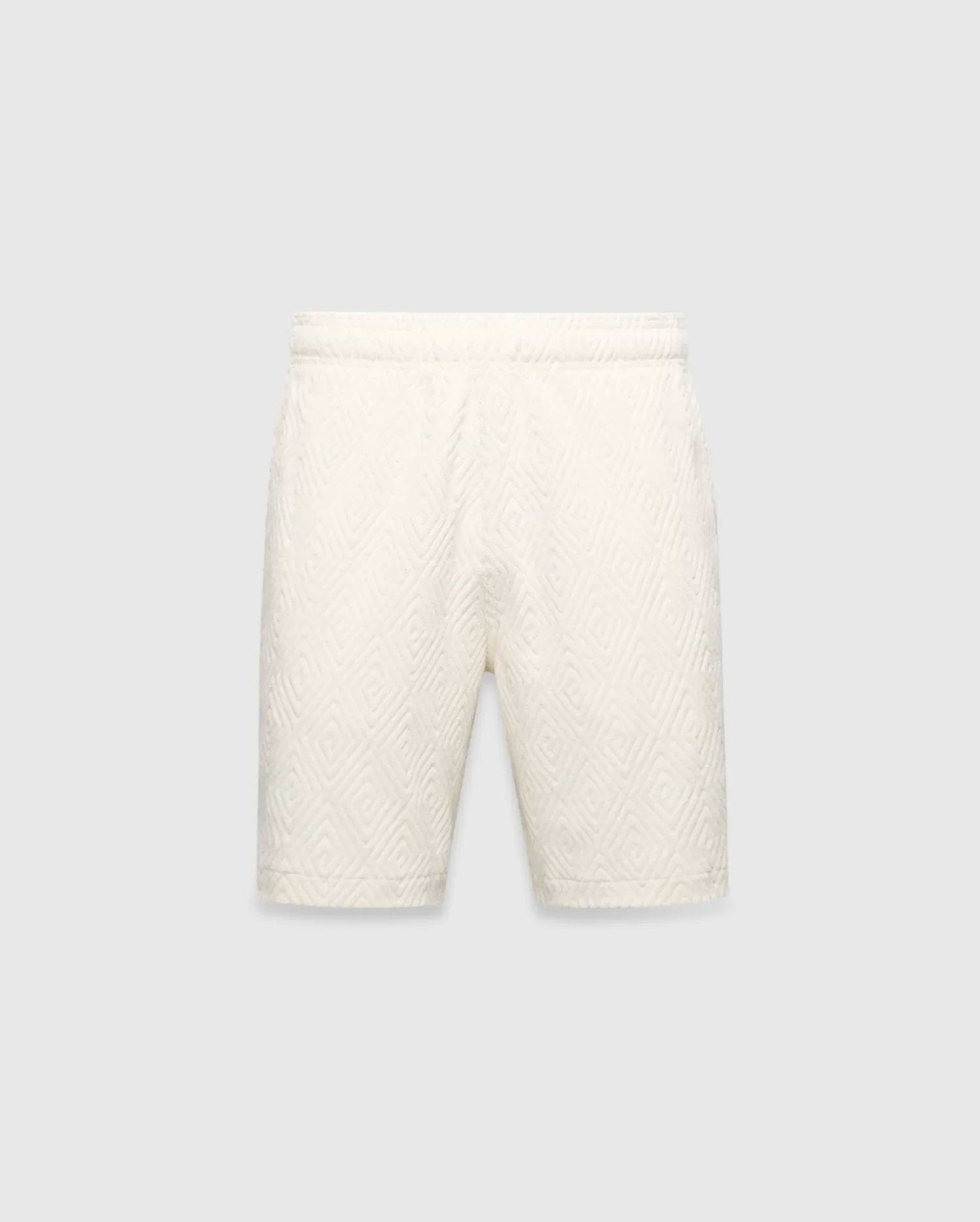 Mens Tristan Short in cream, a relaxed fit short with an all-over raised geometric concentric square pattern on textured fabric, no visible Psycho Bunny logo.